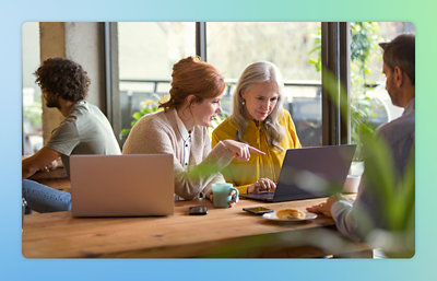 A group of people sitting at a table looking at a laptop.