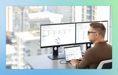 A man sitting at a desk with a laptop and two monitors.