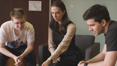 Three people are seated and engaged in a focused discussion. 