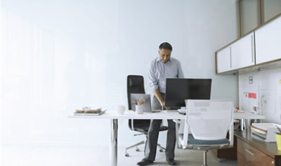 A person standing and working on his desktop in office