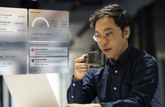 飲み物のカップを片手にノート PC の画面を見るビジネス パーソンと Dynamics 365 の画面