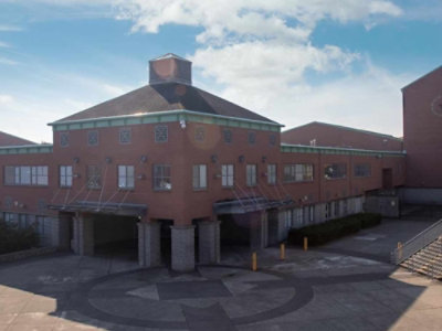 Brick school building with a central courtyard and a large circular emblem on the ground.