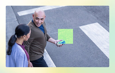 A man holding a phone and a woman standing on the street.