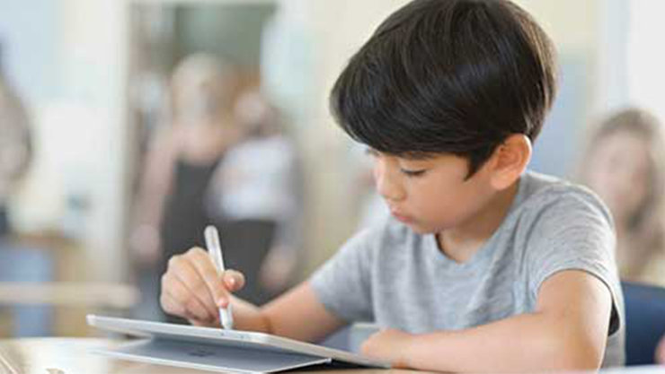 Ein Junge arbeitet mit einem Stift an einem Laptop