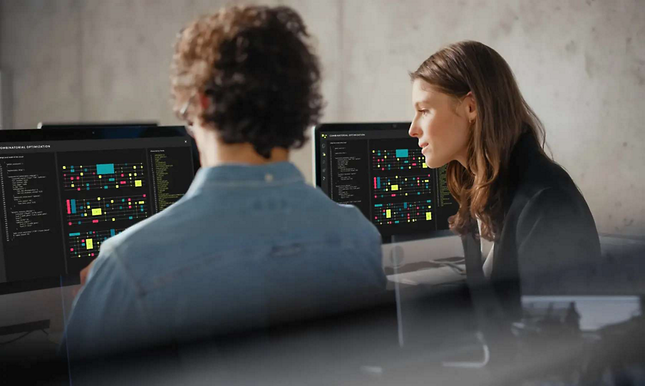 Duas pessoas conversando e olhando para um monitor exibindo software de design de circuito
