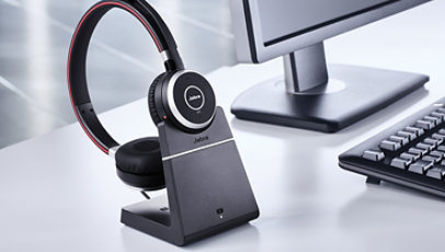 Jabra Evolve 65 charging on a dock next to a computer.