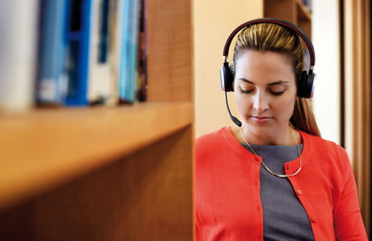 A woman wears Jabra Evolve 65 while working in a library.