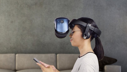 A woman wears the VIVE Cosmos headset over glasses while checking her phone.