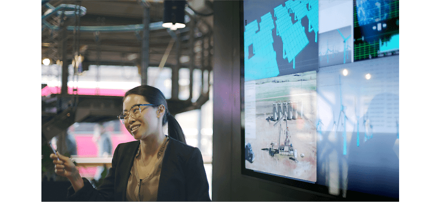 En person som talar framför en vägg med skärmar som visar skisser och data