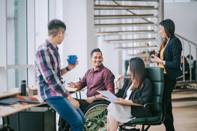A diverse team casually conversing around a work desk setting.