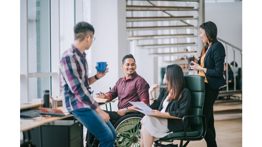 A diverse team casually conversing around a work desk setting.