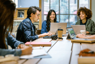 長い机でノート PC を使用して一緒に作業する 4 人の人。