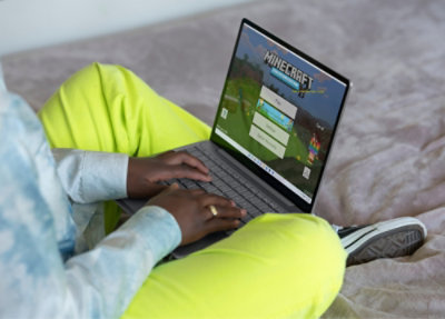 A person using a laptop with minecraft for education opened in it