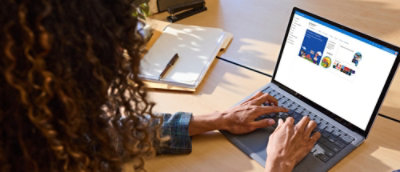 A person with long hairs working on a laptop and using one of the education apps