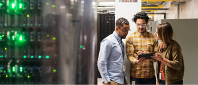 Two individuals standing in a server room with one person holding a tablet.