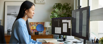 Person working at a desk with multiple computer monitors in an office setting.