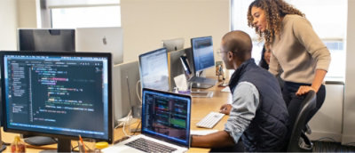 Two people work on computers in an office. 