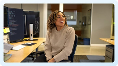 A person sitting in a chair at a desk with a computer screen and a yellow lamp.