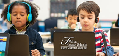 Two children wearing heading with laptops infront of them