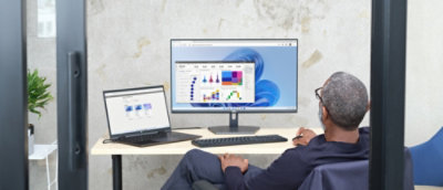 A man in a suit sitting at a desk with a computer and laptop.
