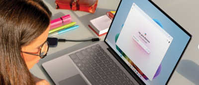 A laptop computer with a book and pen on the table.