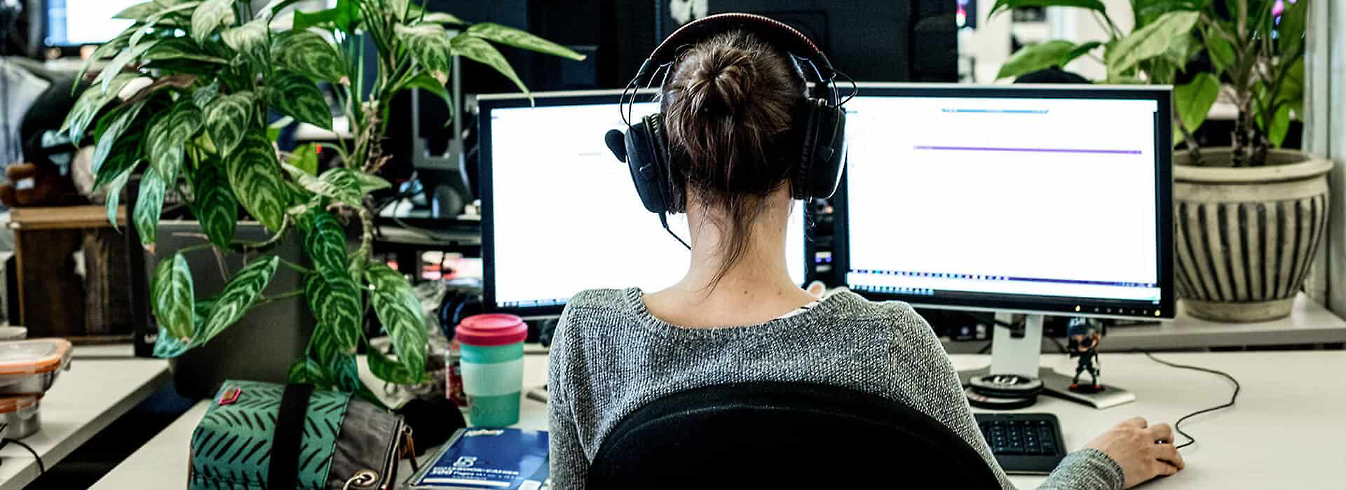 En person med hodetelefoner over øret som jobber ved et skrivebord 