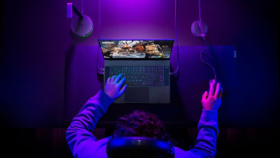 Overhead view of a man playing video games on a Razer Blade 15 Advanced gaming laptop with mouse.