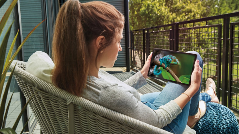 A woman sitting on her patio while watching a video on her Samsung Galaxy Tab S5e.