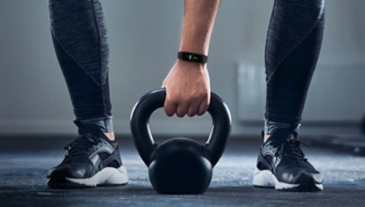 A person wearing the Samsung Galaxy Fit2 Smart Watch lifitng a kettle bell.