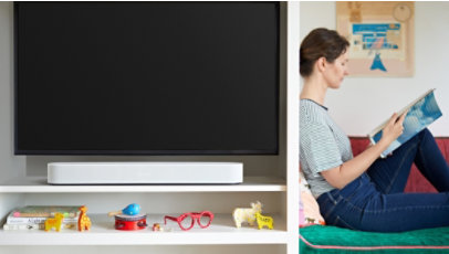 テレビの下の棚に置かれた Sonos Beam からのサウンドを聴いている女性