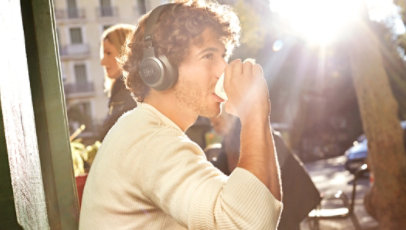 A man wears JBL Headphones in an outdoor cafe.