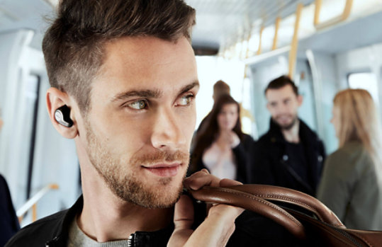 A man listens to Jabra Elite earbuds on a bus.