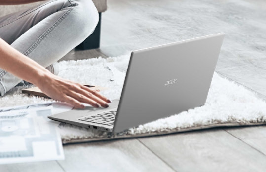 A person seated on a rug using the Acer Swift 3 Laptop