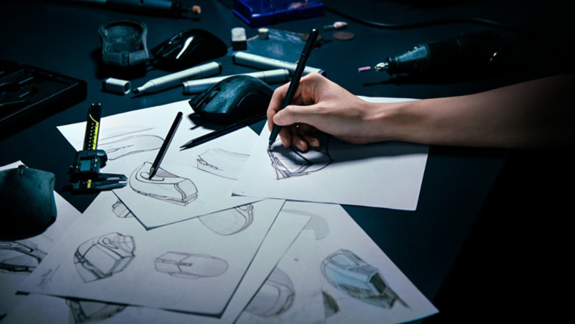 Papers scattered on a desk with design drawings of the Razer DeathAdder V2 Pro Wireless Ergonomic Gaming Mouse.