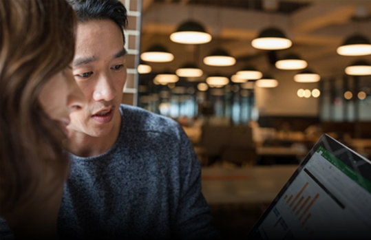 Two coworkers look at a Surface device.