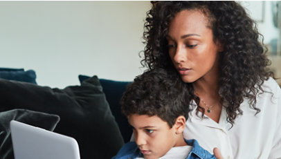 Um pai e uma criança olhando para um laptop Surface aberto juntos em uma sala de estar.