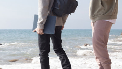 Two people at the beach with a Surface device in hand.