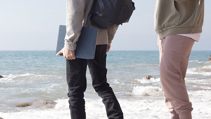 Two people at the beach with a Surface device in hand.