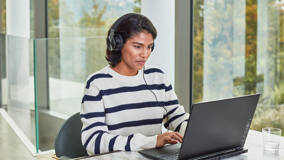 Osoba w biurze, siedząca przy biurku, przy oknie, używająca Szablonów w programie Project na laptopie Surface.