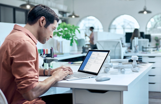 Ein Mann in einem Büro mit einem Surface Book