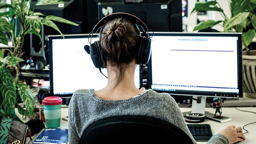 Woman sitting at desk with two monitors