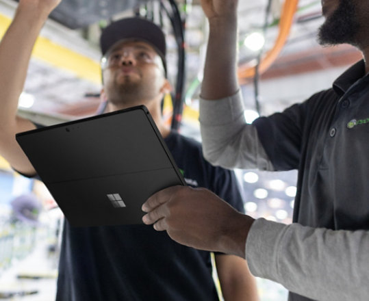 Deux ouvriers d’usine collaborant en utilisant la Surface Pro 6 noire.