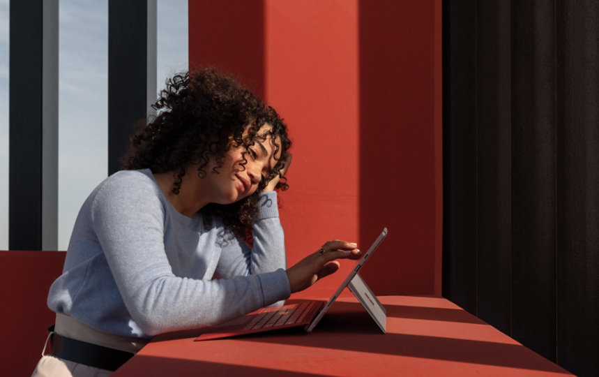 A person uses a Surface device while sitting at a desk.