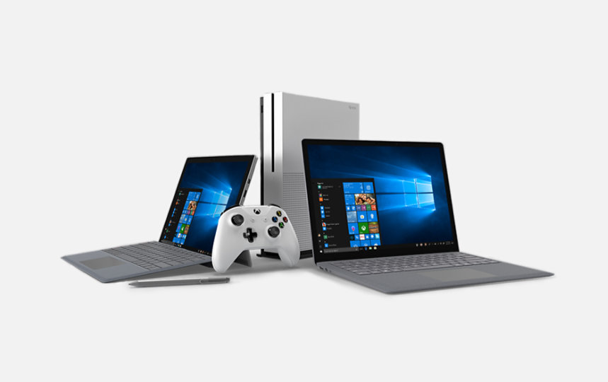 Microsoft Xbox and controller between two Surface devices and pen accessory.