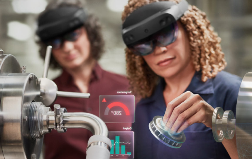 Jedna kobieta używa urządzenia HoloLens w pracy, a inna kobieta ją obserwuje.