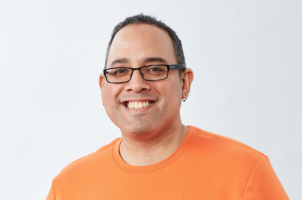 A person in an orange shirt smiling.