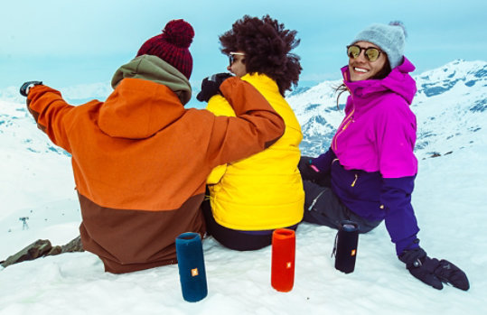 Three people in a snowy landscape with three JBL FLIP 5 speakers