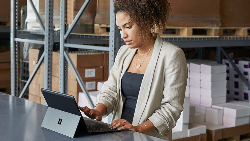 A woman uses her Surface device in a warehouse.