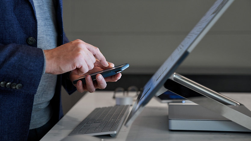 A person uses their phone while at a desk.