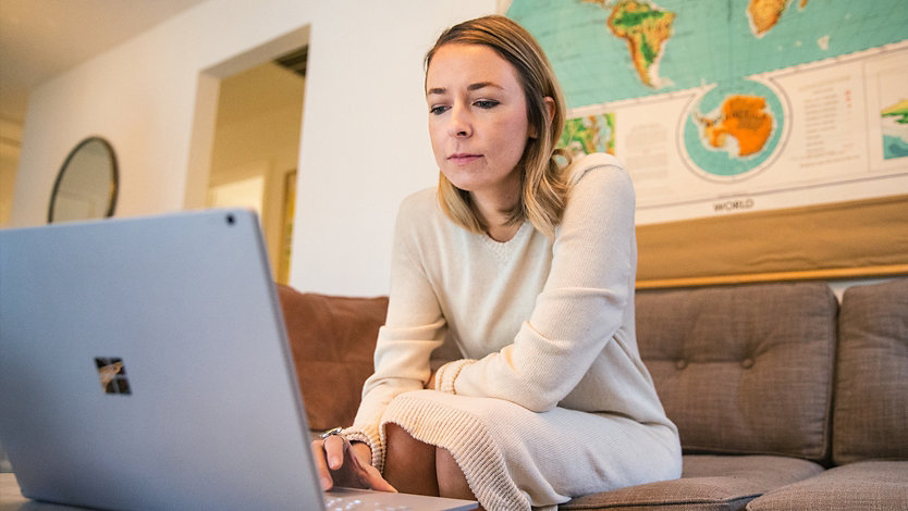 A woman uses her Surface laptop at home.